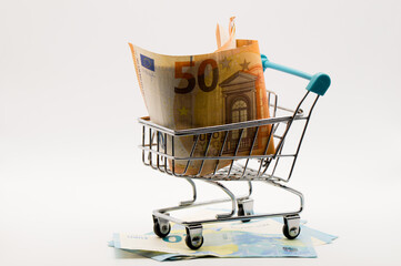 Miniature Shopping Cart Overflowing with Euro Banknotes (50) and Scattered Currency Below