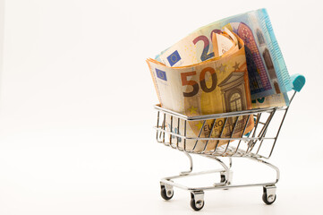 European Financial Growth: Miniature Shopping Cart Overflowing with Euro Banknotes (50, 20) on White Background