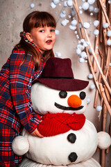 Happy funny little girl child in pajamas hugs a huge soft snowman toy. Magic. Christmas. New Year's eve. St. Nicholas Day. Present. Time of holidays and miracles.	