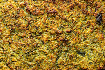 Surface of freshly made baked mücver (courgette and feta bake) as a background texture.