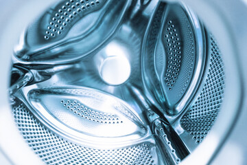 Washing machine drum featuring a sleek design, patterns inside,  effective cleaning. Close-up view of washing machine drum showing its shiny surface,  detailed perforations. Metal silver background.