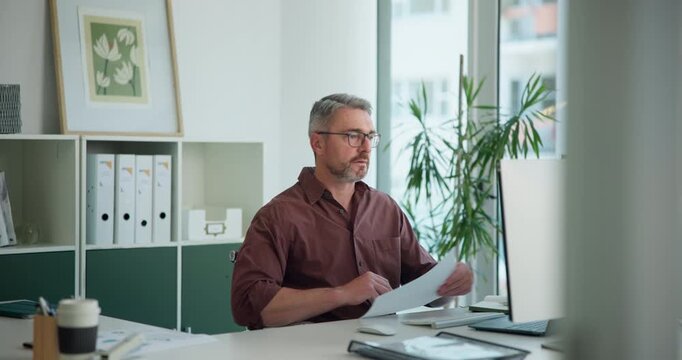 Office, paperwork and man with computer, reading and economist with research on website and thinking. Report, comparison and mature person with tech for inflation rates, online and financial analysis