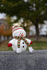 Snowman toy in a warm city, Christmas decoration in urban background, winter in warm country