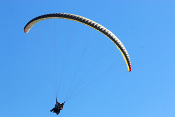 Paraglider flying in a blue sky	