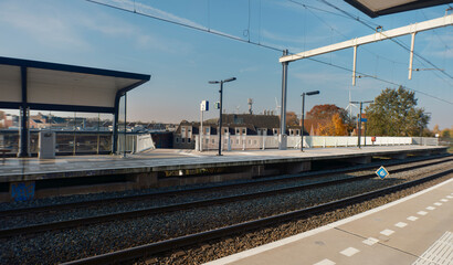 Train station platform with modern shelter structure and railway tracks stretching into distance...
