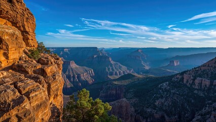 Fototapeta premium Grand Canyon landscape with layered cliffs, blue sky, and a few clouds, showcasing the natural beauty and vastness of the iconic geological formation.