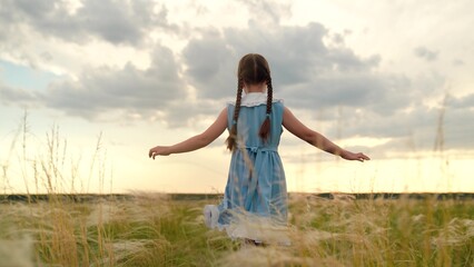 Baby girl playing superhero in nature. kid girl run in park. Happy little girl in dress running with raised hands on grass meadow. Children's dreams. Cheerful little girl play running in summer park