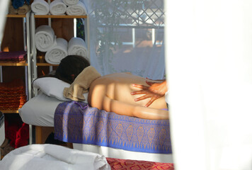 young woman lying on the massage bed during a back therapy session in a luxury exclusive spa with white curtains