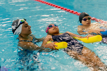 Instructor teaching children floating technique during swimming lesson