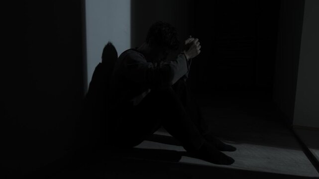 Man trembling with panic attack, shaking hands in darkness, real anxiety symptom