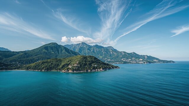 Landscape of mountains and sea with blue sky and clouds, scenic view of coastal mountain range.