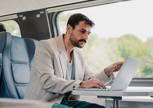 Man working on laptop traveling by train