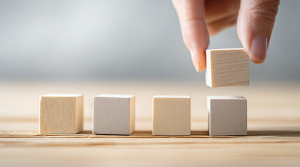 Hand placing wooden cube to build word blocks
