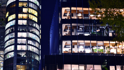 Modern office building in city center illuminated at night. Rows of lit windows against the architectural grid of a modern facade.