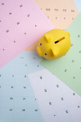 Long-term financial planning. Yellow piggy bank on a multi-colored calendar spread