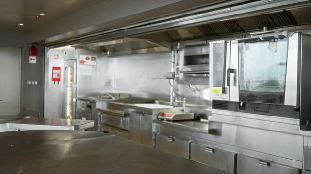 Industrial kitchen interior with soft blurred bokeh foreground and defocused stainless surfaces; background backplate copyspace calm.