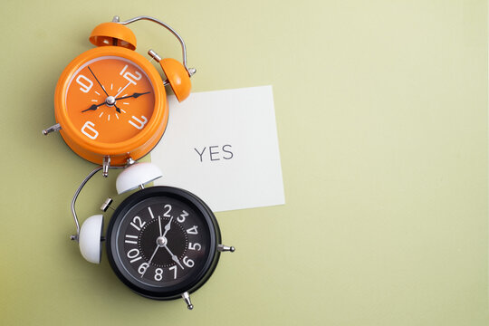 Two alarm clocks with 'YES' note for positive decisions and deadlines. Time for action