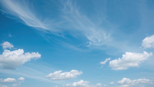 Clear sky with clouds and streaks of cirrus clouds. Bright and sunny weather, peaceful sky scene.