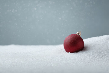 beautifully crafted red christmas ornament resting on blanket of pure untouched snow