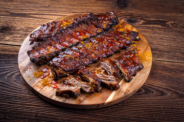 Barbecue smoked hot spicy pork spareribs St Louis cut with curry rub and BBQ sauce on wooden cutting board
