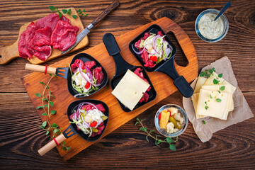 Traditional authentic swiss raclette with beef meat, pickles, savoy cheese and spicy yogurt topping...