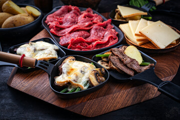 Traditional authentic Swiss raclette with beef meat, boiled potatos, green beans and mushrooms...