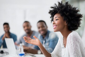 African American woman speaks, gestures, smiles during business meeting with African American men.