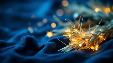Golden wheat stalks with glowing fairy lights on a dark blue fabric. Cozy festive holiday background with bokeh. Rustic winter decoration concept