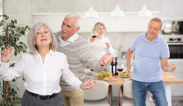 Couples of elderly women and men doing couple dances in kitchen - Powered by Adobe