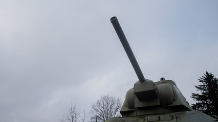 Obraz premium rusty tank turret with pine, historic military monument with weathered tank and surrounding trees