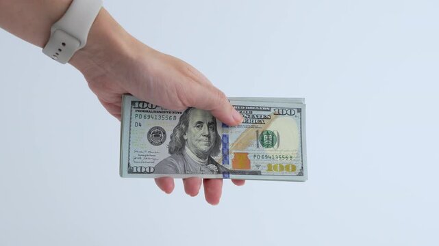 Hand holding stack of cash transitions through frames, showcasing the act of handing over money, with a smooth camera zoom in on details