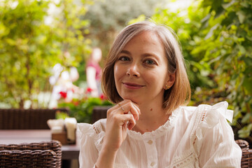 Charming woman enjoying a sunny day in a lush garden cafe setting