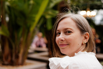 Smiling woman enjoys a lively outdoor gathering surrounded by lush greenery at sunset