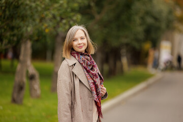 Warm autumn day in the park with a smiling woman wearing a scarf