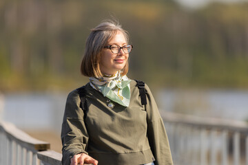 Woman enjoying a peaceful moment by a tranquil lake surrounded by autumn colors in the afternoon sun