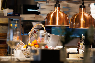 Warm glow from copper lamps illuminates a vibrant fruit basket in a lively kitchen setting