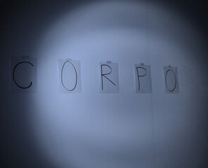 Obraz premium CORPO- Buchstaben im Lichtkegel an der Wand