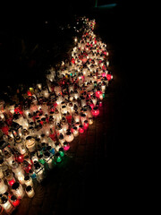 Hundreds of colorful cemetery candles glowing in the dark, forming a bright path of light in remembrance of the departed.