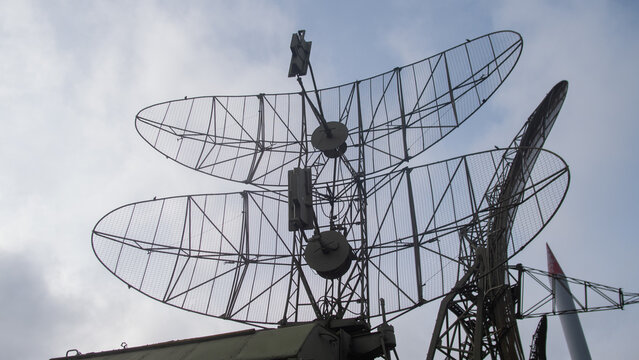 professional technician performs highaltitude inspection on metal dragonfly sculpture against cloudy sky