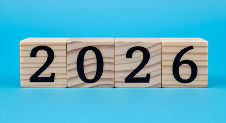 Wooden blocks displaying the year 2026 against a vibrant blue backdrop symbolizing the future new year and upcoming events ideal for calendars invitations and promotional materials for 2026