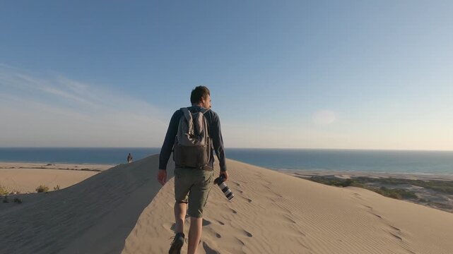 Group of young friends walking in Patara beach sand dunes with golden sand and sea on the background in Turkey, in slow motion