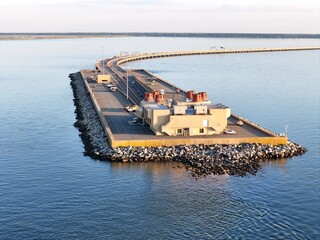 Aerial View Of Long Monitor Merrimac Memorial Bridge Tunnel crossing tranquil blue water of Hampton Roads Channel with a distant harbor and open sky