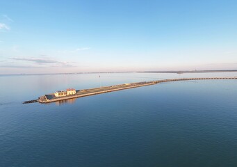 Aerial View Of Long Monitor Merrimac Memorial Bridge Tunnel crossing tranquil blue water of Hampton Roads Channel with a distant harbor and open sky