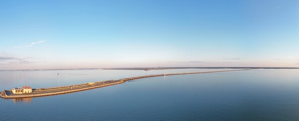 Fototapeta premium Aerial View Of Long Monitor Merrimac Memorial Bridge Tunnel crossing tranquil blue water of Hampton Roads Channel with a distant harbor and open sky