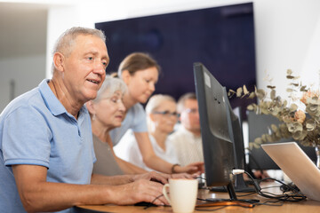 Enthusiastic senior man attending computer class, highlighting interest and initiative of older people to embrace digital education..