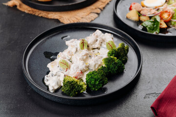 Creamy chicken with broccoli on black plate, restaurant gourmet lunch closeup