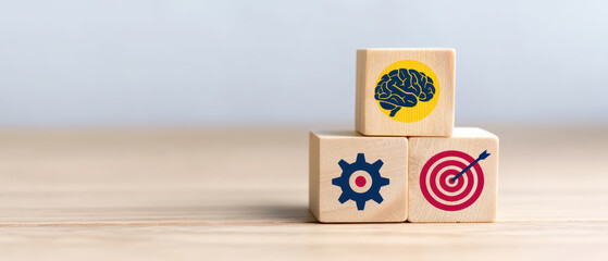 Wooden blocks stacked with of brain, gear, and target symbolizing intelligence, strategy, and goal achievement on wooden surface with soft background