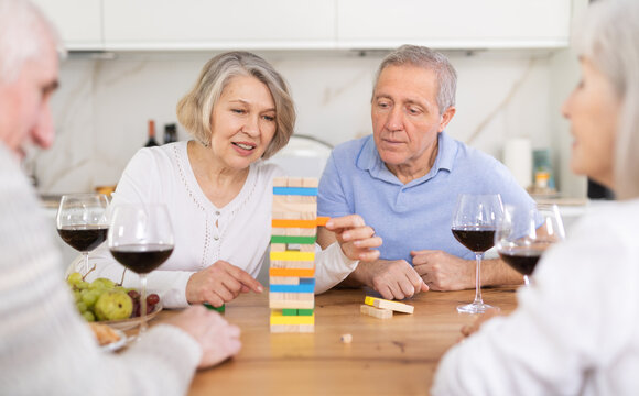 Elderly man and woman friends playing board game bricks at table