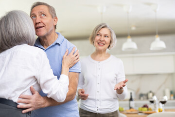 After chatting and gatherings, senior woman hug and kiss goodbye with male pensioner friend