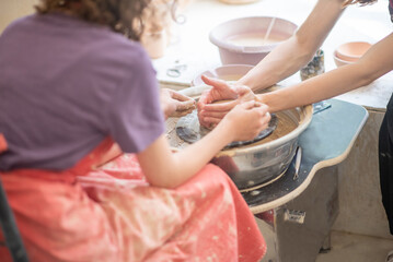 Close-up portrait of a smiling young girl in an apron in a pottery studio. Joyful child surrounded by unfired clay ceramics, emphasizing creative learning and hands-on craft.